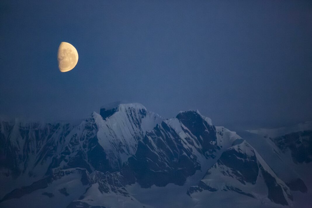 last quarter moon rising over mountains